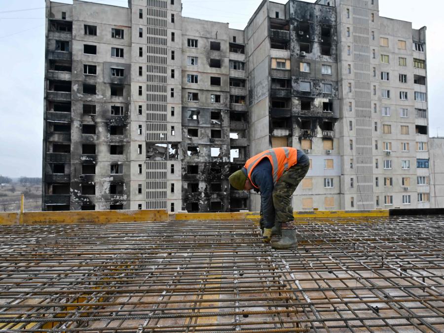 Un costruttore controlla i lavori, mentre il tetto di un condominio viene ristrutturato dopo essere stato parzialmente distrutto dai bombardamenti, nella città ucraina di Kharkiv. (Photo by SERGEY BOBOK / AFP)