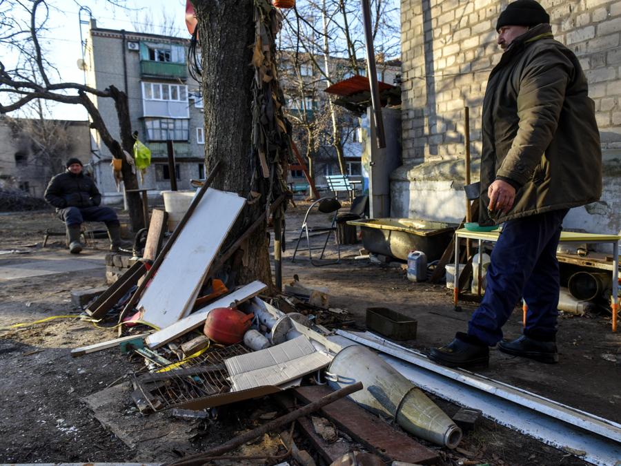 Alcune persone accanto al grappolo di un missile Uragan nel cortile di un edificio residenziale nella città di Siversk, regione di Donetsk. (EPA/Oleg Petrasyuk)
