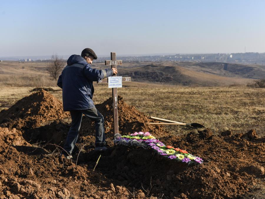 Un addetto alle pompe funebri pone una croce su una nuova tomba a Bakhmut, nella regione di Donetsk, nell’Ucraina orientale. (EPA/Oleg Petrasyuk)
