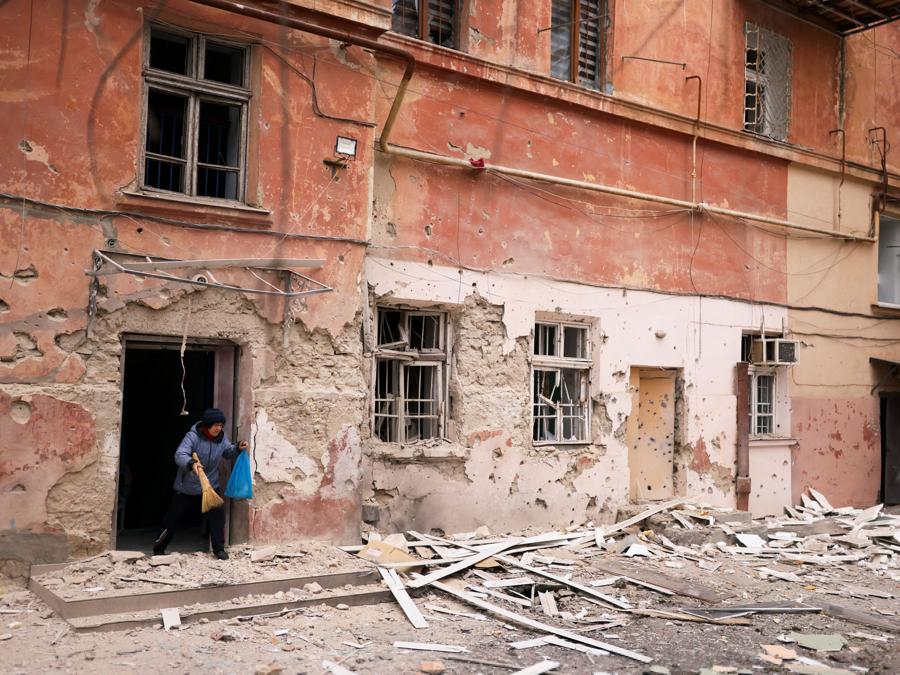 Una donna rimuove i detriti davanti al suo appartamento in un edificio  danneggiato da un attacco militare russo,  a Kherson. (REUTERS/Nacho Doce)