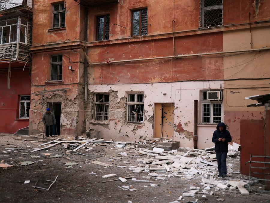 Due persone camminano davanti al loro condominio danneggiato da un attacco militare russo,  a Kherson. (REUTERS/Nacho Doce)