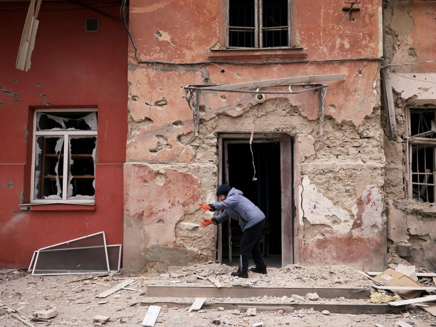 Una donna rimuove i detriti davanti al suo appartamento  danneggiato da un attacco militare russo,  a Kherson. (REUTERS/Nacho Doce) 
