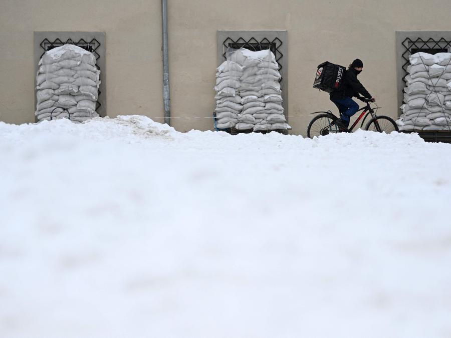 Un ciclista passa accanto a sacchi di sabbia ricoperti di neve nella città ucraina occidentale di Lviv. (Photo by YURIY DYACHYSHYN / AFP)