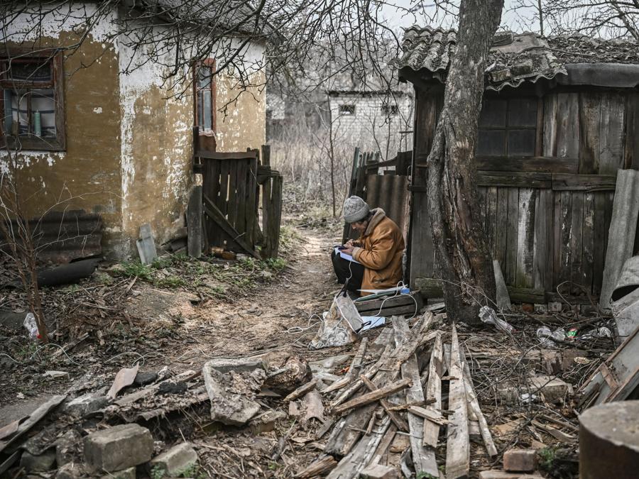 Una donna prende appunti e usa il suo smartphone mentre siede nel cortile di una casa nella città di Chasiv Yar, vicino a Bakhmut. (Photo by Aris Messinis / AFP)