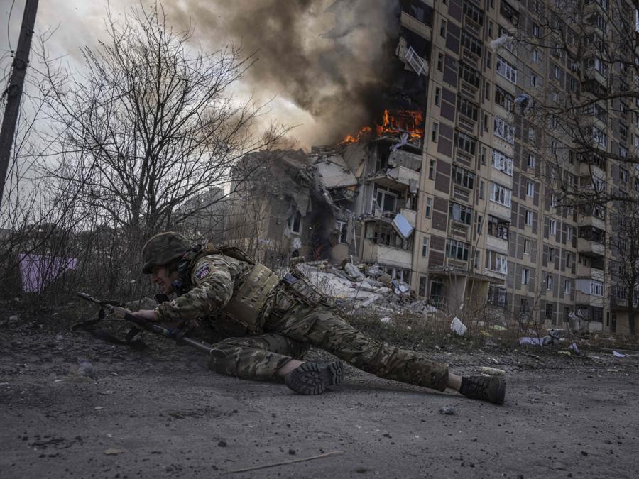 Un agente di polizia ucraino si mette al riparo davanti a un edificio in fiamme colpito da un attacco aereo russo ad Avdiivka, in Ucraina,. (AP Photo/Evgeniy Maloletka) Associated Press/LaPresse