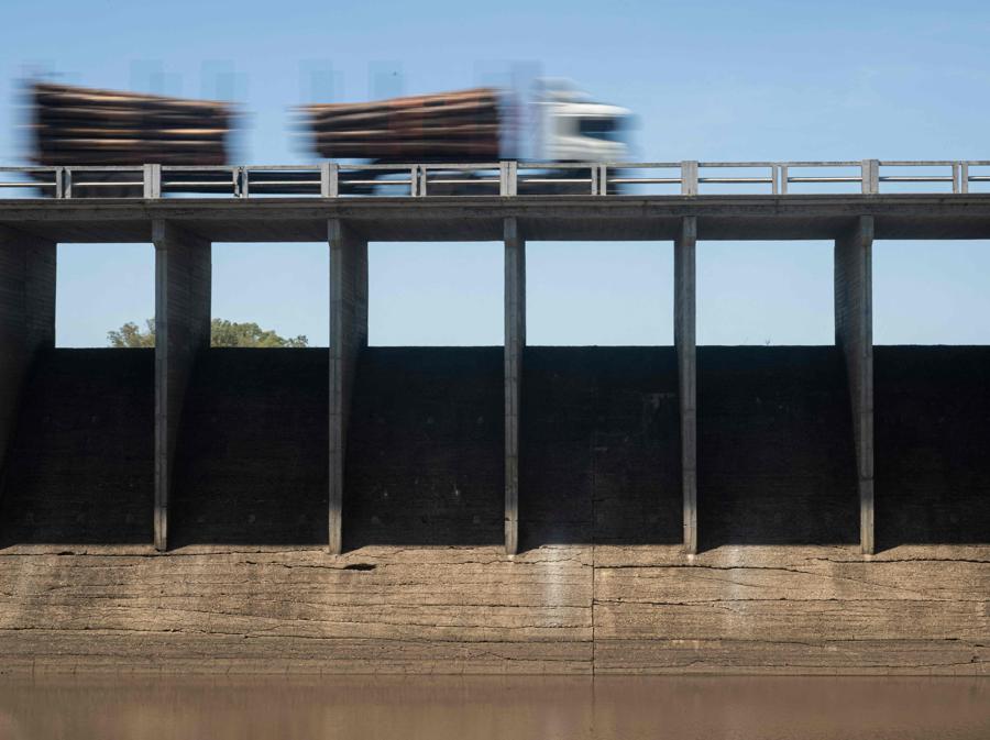 Un camion che trasporta tronchi percorre la Route 5 sopra il ponte-diga presso il bacino prosciugato di Canelon Grande appena a nord di Canelones, nel sud dell’Uruguay, mentre il paese attraversa una grave siccità. - Lo scopo principale del serbatoio è quello di fornire acqua potabile all’area metropolitana di Montevideo, mentre viene utilizzato anche nei sistemi di irrigazione della zona. (Photo by Pablo PORCIUNCULA / AFP)
