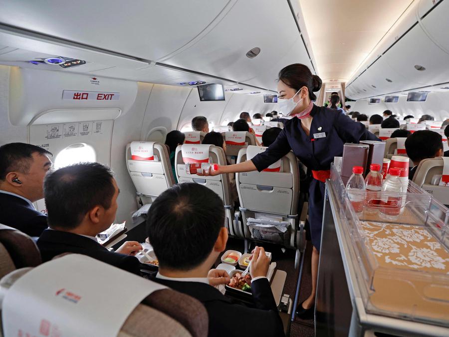 Un’ assistente di volo distribuisce bottiglie d’acqua ai passeggeri durante il primo volo commerciale del primo aereo passeggeri cinese C919 da Shanghai a Pechino il 28 maggio 2023.(AFP)