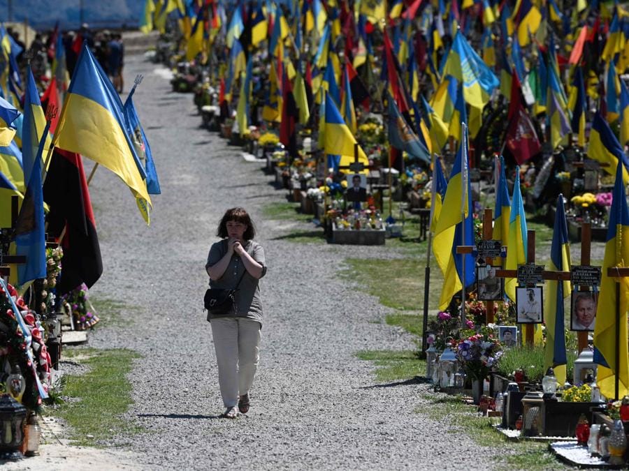 Una donna cammina tra le tombe del cimitero militare di Lychakiv nella città ucraina occidentale di Lviv. (Photo by YURIY DYACHYSHYN / AFP)