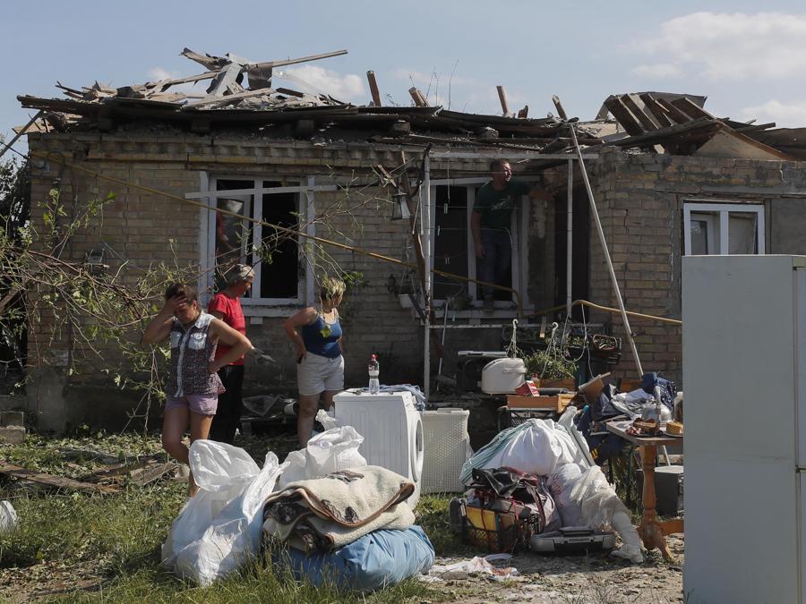Alcune persone recuperano gli effetti personali, nel villaggio di Stari Petrivtsi vicino a Kiev, colpito dalla caduta di detriti da un razzo. (Epa/Sergey Dolzhenko)