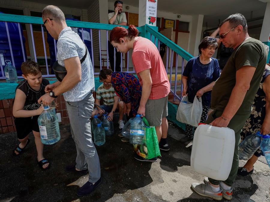 I residenti locali riempiono le loro bottiglie di plastica in un punto  di distribuzione dell’acqua, mentre non c’è approvvigionamento idrico in città dopo che il livello dell’acqua nel bacino idrico di Kakhovka è calato bruscamente a causa della distruzione della diga di Kakhovka,  a Nikopol, nella regione di Dnipropetrovsk. (Reuters/Alina Smutko)