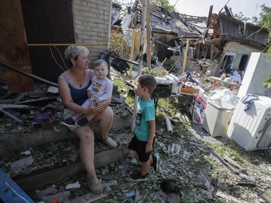 Una donna coi suoi bambini tra le maceria della loro casa colpita dalla caduta di detriti da un razzo, nel villaggio di Stari Petrivtsi vicino a Kiev. (Epa/Sergey Dolzhenko)
