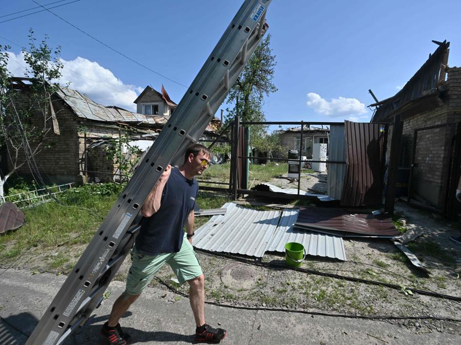 I residenti passano davanti a case distrutte nel villaggio di Stari Petrivtsi fuori Kiev a seguito di un attacco missilistico russo. (Photo by Genya Savilov / Afp)