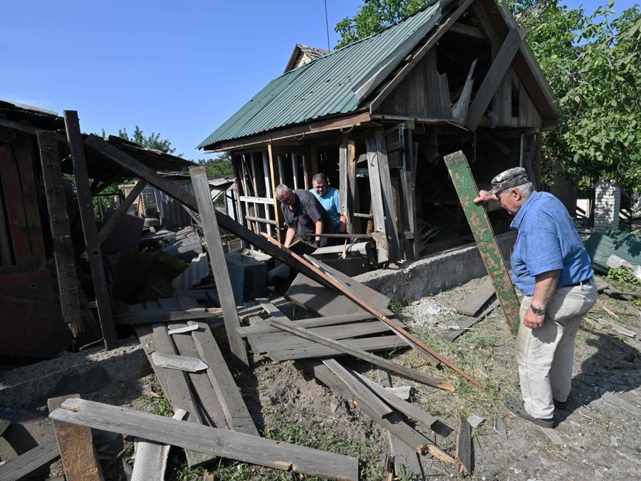 I residenti rimuovono i detriti di un fienile distrutto a seguito di un attacco missilistico russo nel villaggio di Stari Petrivtsi fuori Kiev. (Photo by Genya Savilov / Afp)