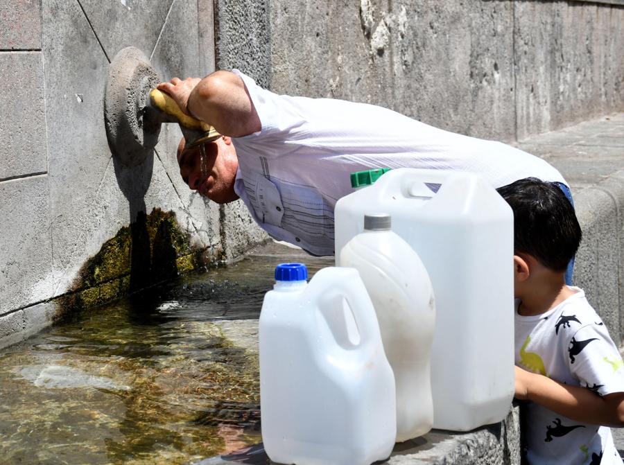 Una famiglia si disseta ad una fonte e riempie le taniche e bidoni di acqua, a causa dei problemi dovuti alla distribuzione ed i continui disservizi che hanno lasciato senz’acqua interi quartieri cittadini, nel quartiere Cibali a Catania (Ansa/(Orietta Scardino) 
