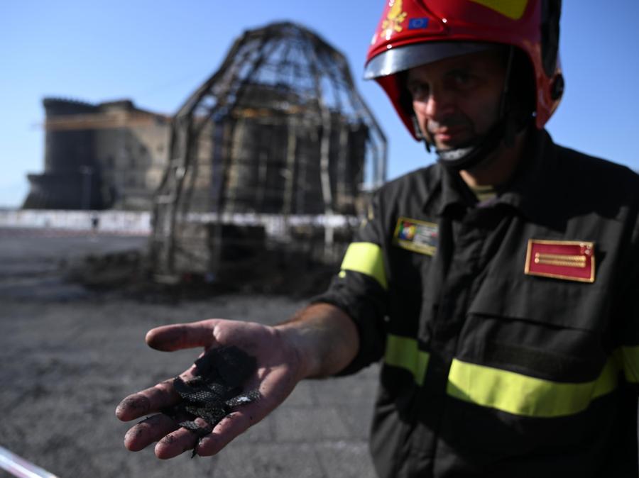 Un vigile del fuoco davanti alla installazione 'Venere degli stracci, completamente distrutta da un incendio, in piazza Municipio a Napoli. (ANSA/ CIRO FUSCO)