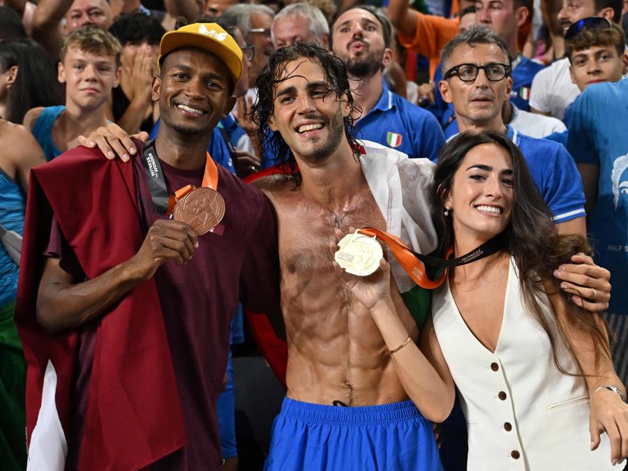 Gianmarco Tamberi e sua moglie,  festeggiano con Mutaz Essa Barshim, terzo classificato del Qatar. (Photo by Andrej Isakovic / Afp)