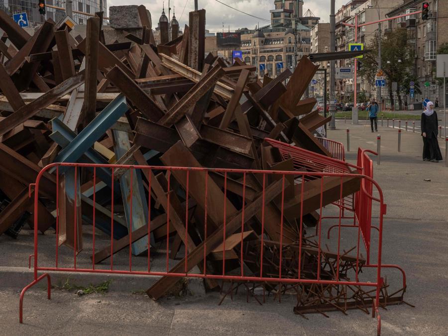 Una donna passa davanti a un mucchio di barriere di metallo per carri armati nel centro di Kiev. (Photo by Roman PILIPEY / AFP)