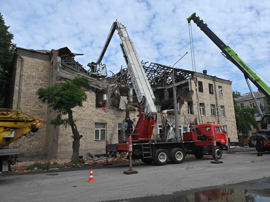 I soccorritori rimuovono i detriti dopo che un drone ha colpito un istituto scolastico, a Kharkiv. (Photo by Sergey Bobok / Afp)