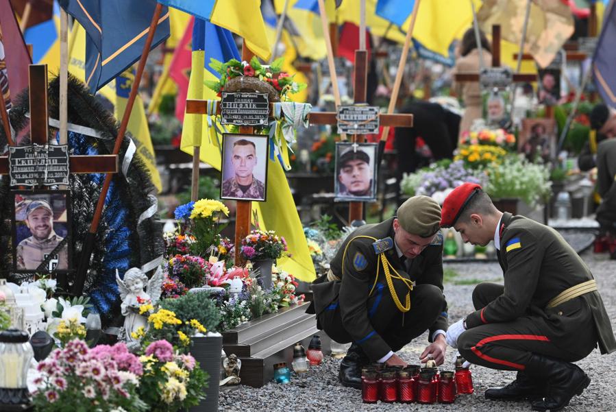 I cadetti accendono candele mentre rendono omaggio ai soldati ucraini caduti nel cimitero di Lychakiv per celebrare la Giornata dei difensori dell’Ucraina a Lviv, nel mezzo dell’invasione russa dell’Ucraina. (Photo by YURIY DYACHYSHYN / AFP)