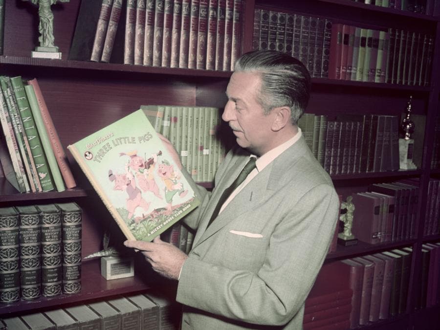American film producer Walt Disney (1901 - 1966) holding a Mickey Mouse Club edition of the 'Three Little Pigs' story, circa 1955. (Photo by Silver Screen Collection/Getty Images)