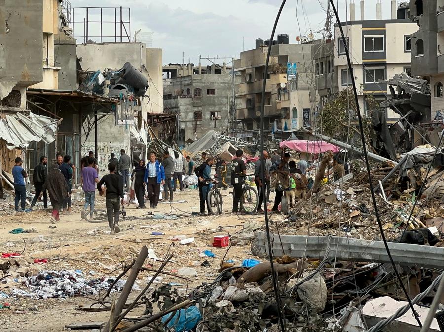 Palestinesi passano davanti alle case danneggiate dagli attacchi israeliani durante il conflitto, nel mezzo di una tregua temporanea tra Israele e Hamas, nel nord della Striscia di Gaza. (Reuters/Abed Sabah)