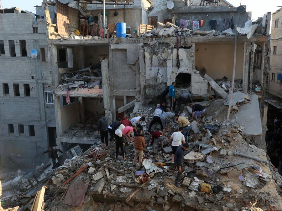 Palestinesi osservano la distruzione attorno agli edifici residenziali in seguito agli attacchi aerei israeliani nel campo profughi di Rafah, nel sud della Striscia di Gaza. (Photo by SAID KHATIB / AFP)