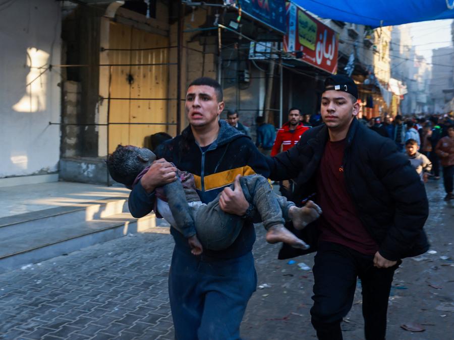 Un uomo palestinese trasporta un ragazzo ferito in seguito alla ripresa dei bombardamenti israeliani a Rafah, nel sud della Striscia di Gaza. (Photo by MOHAMMED ABED / AFP)