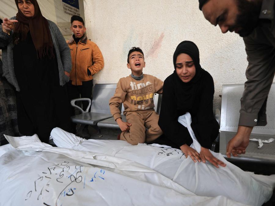 I parenti di Jehad Arafat, ucciso dai bombardamenti israeliani, piangono sul suo corpo prima del suo funerale presso l’ospedale Najar di Rafah, nel sud della Striscia di Gaza. (Photo by Mahmud HAMS / AFP)
