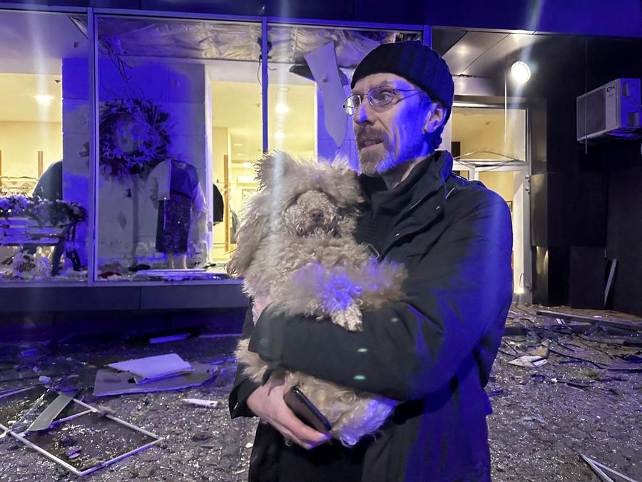 Un residente tiene in braccio il suo cane vicino al luogo di un bombardamento russo a Kharkiv, Ucraina. (Reuters)