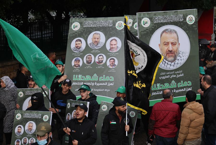 Alcune persone portano con sé i ritratti del vice leader di Hamas, Saleh al-Aruri e di altri funzionari uccisi. (Photo by Anwar Amro / AFP)