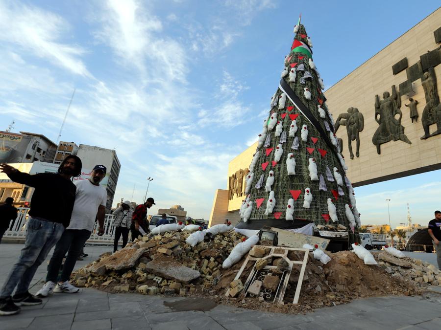 Iracheni camminano vicino a un albero di Natale decorato con bare simboliche che rappresentano le vittime di Gaza in piazza Tahrir nel centro di Baghdad, Iraq. EPA/AHMED JALIL