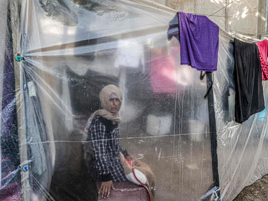 Una donna guarda da dietro un telo di plastica mentre siede accanto ai vestiti stesi su una corda per il bucato in un campo che ospita palestinesi sfollati fuori dall’ospedale europeo di Khan Yunis, nel sud della Striscia di Gaza. (Photo by AFP)