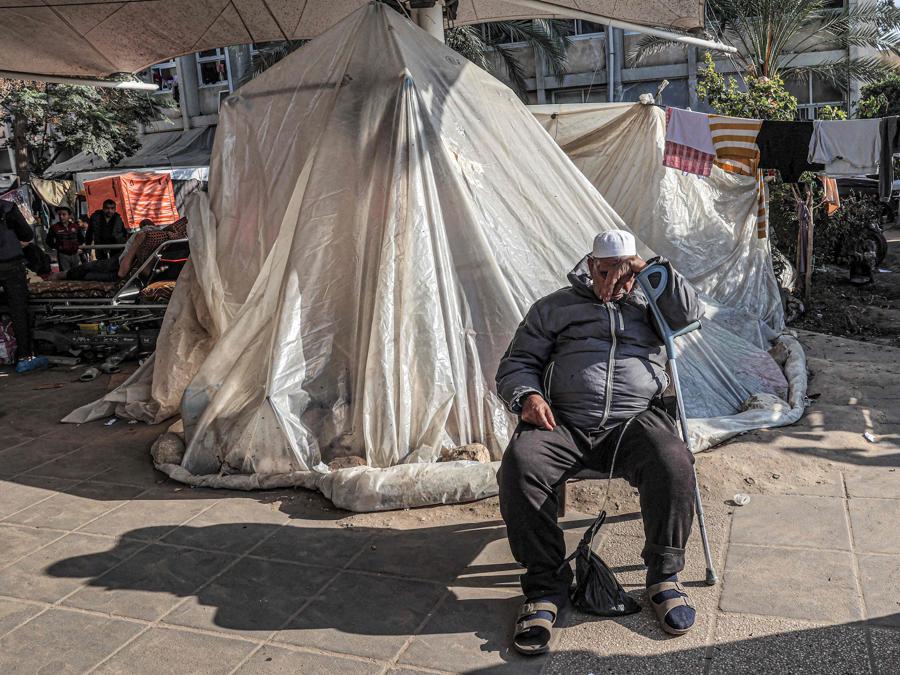 Un uomo si riposa appoggiato a una stampella fuori da una tenda dove sono accampati palestinesi sfollati fuori dall’ospedale europeo di Khan Yunis, nel sud della Striscia di Gaza. (Photo by AFP)