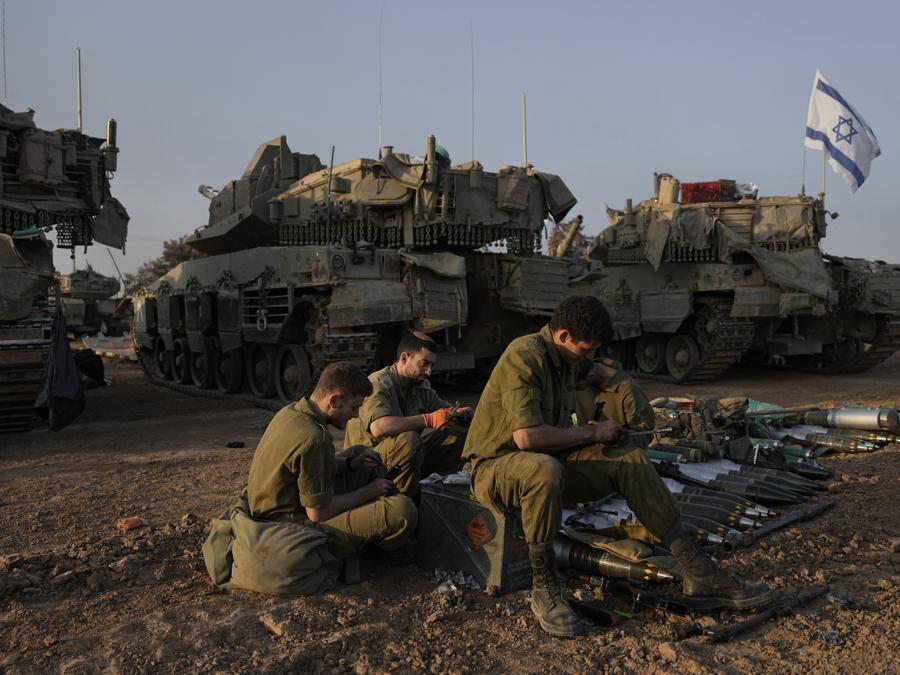Soldati israeliani lavorano sui carri armati in un’area di sosta nel sud di Israele vicino al confine con Gaza. (AP Photo/Ohad Zwigenberg)