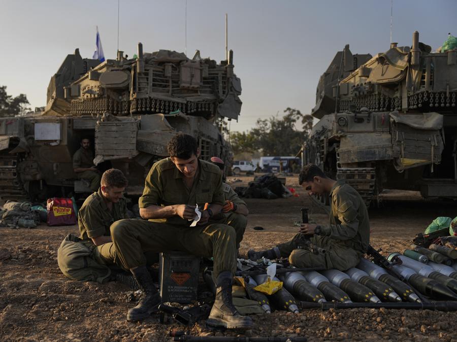 Soldati israeliani lavorano sui carri armati in un’area di sosta nel sud di Israele vicino al confine con Gaza. (AP Photo/Ohad Zwigenberg)