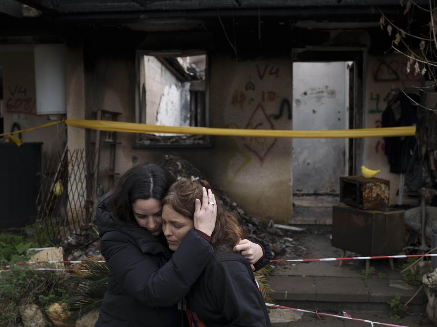 Amit Soussana, 40 anni, a destra, viene abbracciata da un’amica dopo aver parlato con i giornalisti davanti alla sua casa distrutta nel kibbutz Kfar Azza, vicino alla Striscia di Gaza, Israele. (AP Photo/Leo Correa)