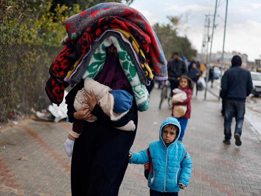 Una donna tiene in braccio un bambino mentre i palestinesi in fuga da Khan Younis, a causa dell’operazione di terra israeliana, si dirigono verso Rafah, nel mezzo del conflitto in corso tra Israele e il gruppo islamico palestinese Hamas, nel sud della Striscia di Gaza. REUTERS/Mohammed Salem 