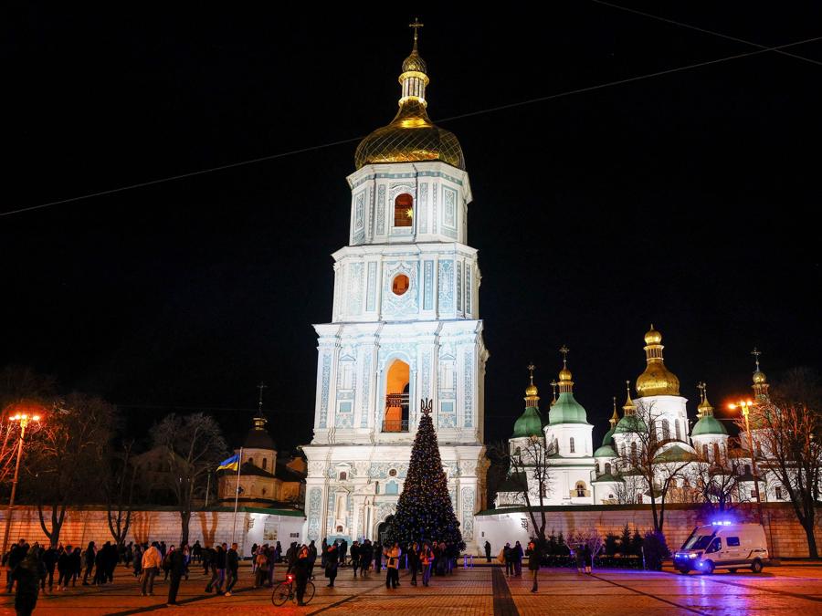 Le persone si sono radunate accanto a un albero di Natale per celebrare la vigilia di Capodanno, nel mezzo dell’invasione russa in corso in Ucraina, di fronte alla Cattedrale di Santa Sofia a Kiev, Ucraina. REUTERS/Valentyn Ogirenko