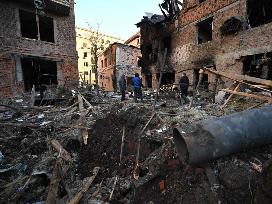I residenti locali ispezionano i danni all’esterno di un condominio dopo l’attacco notturno di droni russi a Kharkiv. (Photo by SERGEY BOBOK / AFP)