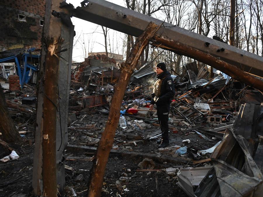 Un poliziotto esamina i danni all’esterno di un condominio dopo l’attacco notturno di droni russi a Kharkiv. (Photo by SERGEY BOBOK / AFP)