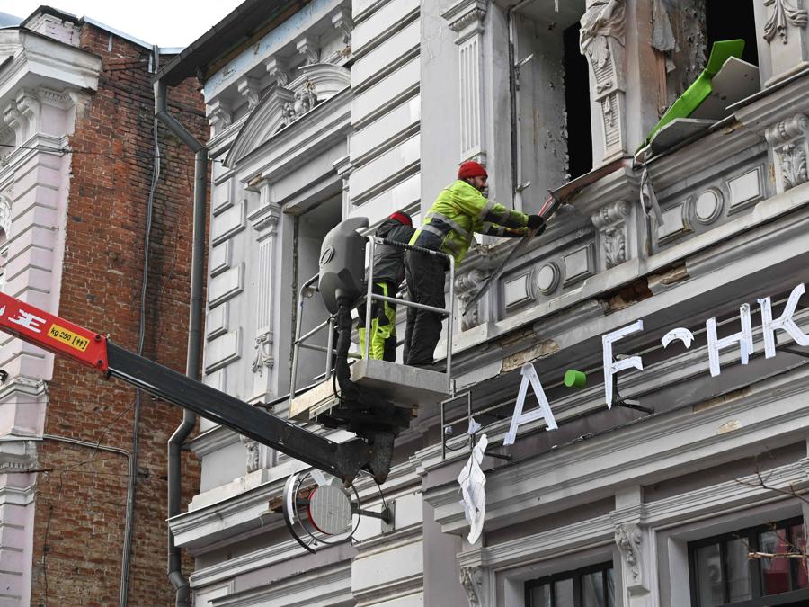 Gli operatori dei servizi pubblici ripuliscono i detriti e le finestre rotte in seguito a un attacco di droni russi a Kharkiv. (Photo by SERGEY BOBOK / AFP)