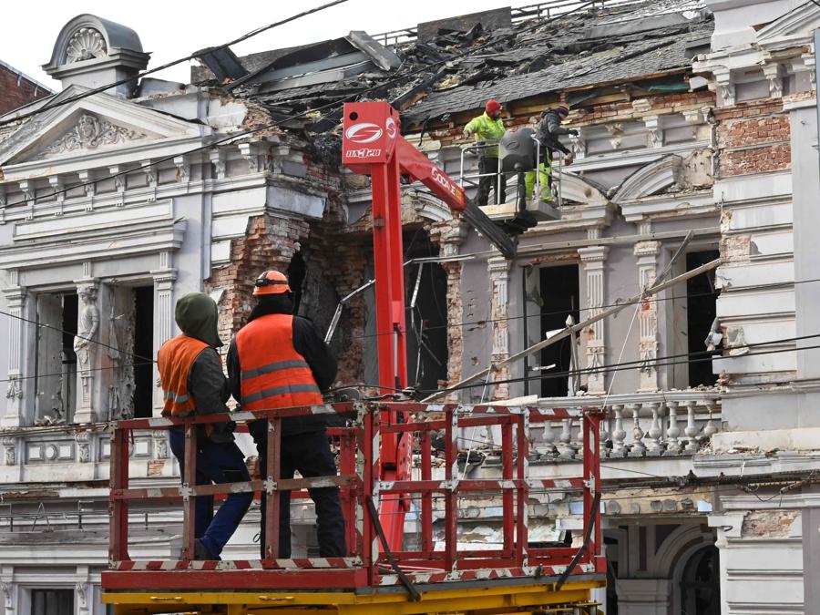 Gli operatori dei servizi pubblici ripuliscono i detriti e le finestre rotte in seguito a un attacco di droni russi a Kharkiv. (Photo by SERGEY BOBOK / AFP)