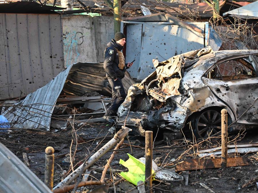 Un poliziotto esamina i danni all’esterno di un condominio dopo l’attacco notturno di droni russi a Kharkiv. (Photo by SERGEY BOBOK / AFP)