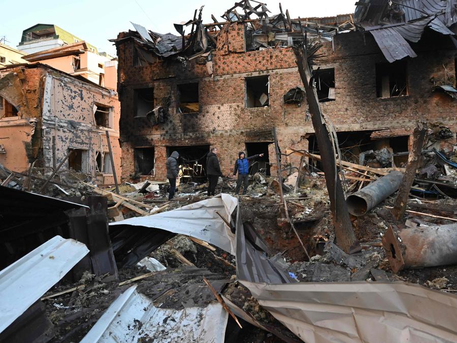 I residenti locali ispezionano i danni all’esterno di un condominio dopo l’attacco notturno di droni russi a Kharkiv. (Photo by SERGEY BOBOK / AFP)