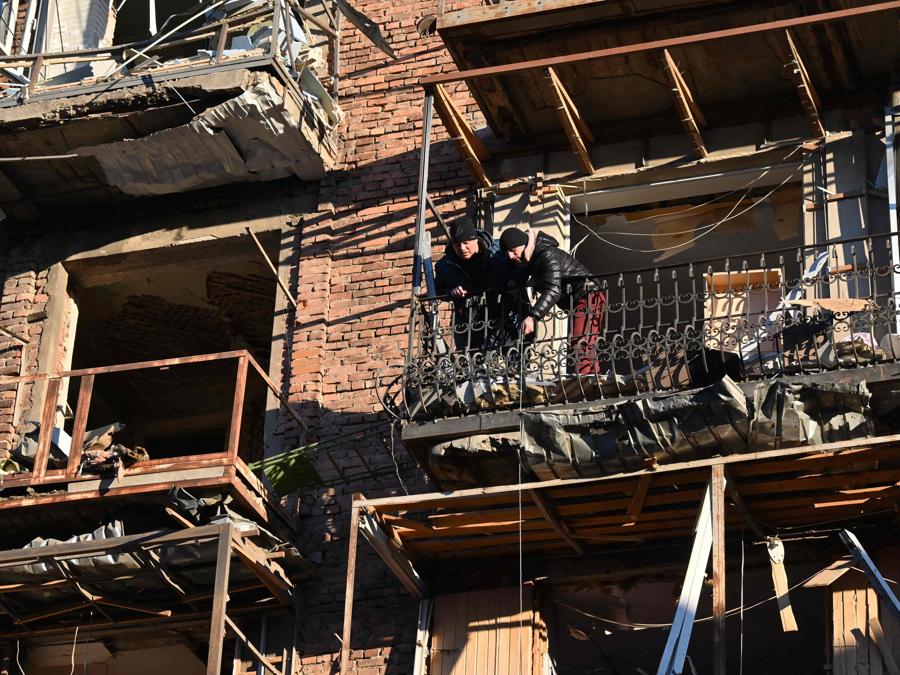 I residenti locali si trovano sul balcone di un condominio dopo l’attacco notturno di droni russi a Kharkiv. (Photo by SERGEY BOBOK / AFP)