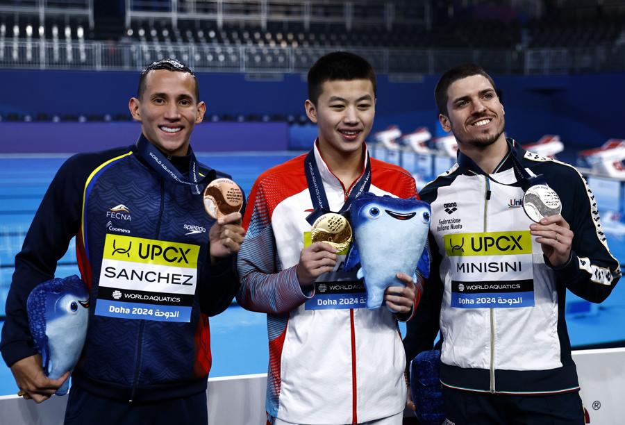 5 febbraio 2024  - Il podio del nuoto artistico:  la medaglia d’oro cinese Shuncheng Yang festeggia dopo aver vinto la finale tecnica in solitario maschile insieme alla medaglia d’argento dell’italiano Girogio Minisini e alla medaglia di bronzo del colombiano Gustavo Sanchez. Campionati mondiali di nuoto, Doha, Qatar.(REUTERS/Clodagh Kilcoyne)