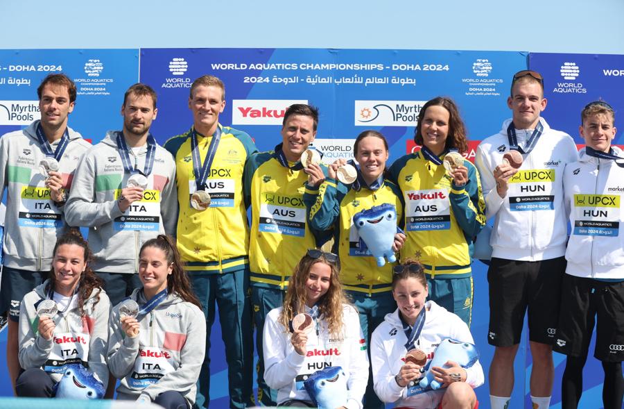 8 febbraio 2024 - Al centro la squadra australiana  medaglia d’oro, a sinistra la squadra italiana medaglia d’argento  e a destra la squadra ungherese medaglia di bronzo posano durante la cerimonia di premiazione alla staffetta mista in acque libere 4x1500 m ai Campionati mondiali di nuoto FINA di Doha 2024 in Qatar. (EPA/Ali Haider)