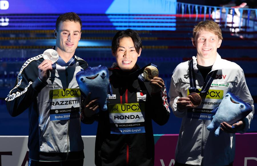 14 Febbraio 2024 -  Sul podio da sinitra l’italiano Alberto Razzetti medaglia d’argento, il giapponese medaglia d’oro Tomoru Honda e l’austriaco Martin Espernberger medaglia di bronzo   posano dopo la cerimonia di premiazione della finale dei 200 metri farfalla maschile ai Campionati mondiali di nuoto FINA Doha 2024. (EPA/Ali Haider)