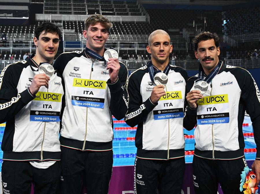 11 febbraio 2024 - Il Team italiano festeggia la medaglia d’argento sul podio della staffetta maschile 4X100m stile libero durante i Campionati mondiali di nuoto 2024 all’Aspire Dome di Doha. (Photo by Sebastien Bozon / AFP)