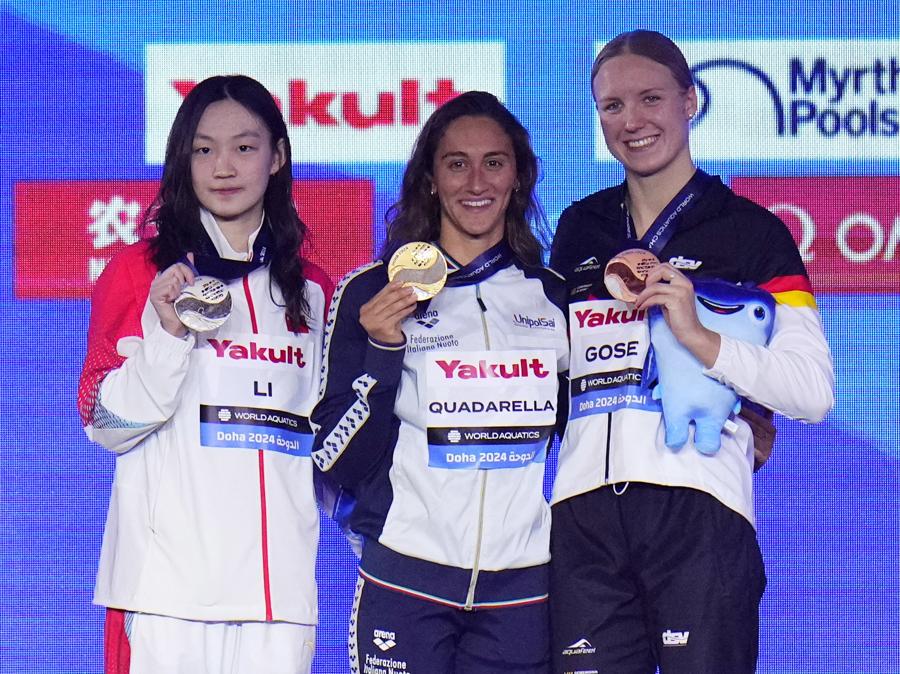 13 febbraio 2024  - Sul podio della finale dei 1500 metri stile libero femminile ai Campionati mondiali di nuoto di Doha: al centro Simona Quadarella medaglia d’oro, festeggia affiancata a sinistra dalla cinese Li Bingjie medaglia d’argento, e dalla tedesca Isabel Gose  medaglia di bronzo. (AP Photo/Hassan Ammar)